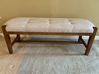 Side view of the wooden bench showing upholstered seat in grey chevron fabric and wooden frame with horizontal support bar.