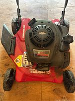 Top view of the red Hyper Tough lawn mower showcasing the Briggs & Stratton E300 Prime engine with model and specifications label.