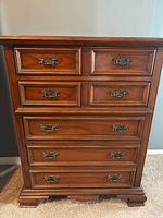 Front view of wooden chest of drawers with six drawers and ornate metal handles, showing good condition and mid-century styling.