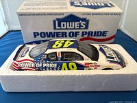 Side and top view of Lowe's Power of Pride 1:24 scale stock car replica inside foam packaging with original box behind.