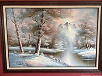 Framed oil painting showing detailed winter landscape with snow, trees, river, and mountains.