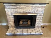 Front view of the electric fireplace with mantel showing faux brick surround and wooden top shelf with carving detail.
