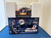 Diecast car displayed inside clear protective case with white foam corners on top of the branded blue box featuring Rusty Wallace and Miller Lite graphics.