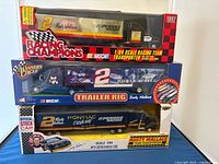 Front view of three 1/64 scale Rusty Wallace die-cast transporters in unopened retail packaging stacked vertically showing box graphics and branding.