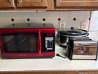 Microwave oven, toaster, and slow cooker together on kitchen counter showing the overall lot contents
