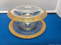 Glass dessert compote showing the wide gold floral encrusted rim and clear glass pedestal base.