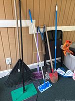 Photo of assorted garden and cleaning tools standing against a wall inside a room