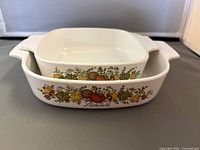 Two nested CorningWare casserole dishes in Spice of Life pattern viewed from above showing vegetable motif and handles.