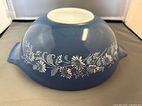 View of the bottom of the Pyrex bowl showing light blue color with white floral pattern and embossed usage instructions.