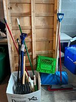 Wide view showing entire lot including brooms, shovels, dustpan in a box and crate propped against wall