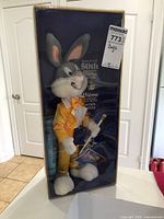 Full view of Bugs Bunny plush in original box, dressed in yellow suit holding cane, visible through clear plastic window.