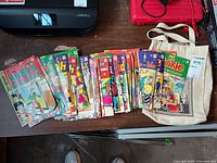 Full collection spread showing approx. 30-40 Archie comics including Archie's Pals 'n' Gals, Josie and the Pussycats, and others, along with a tote bag on the side.