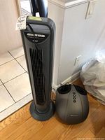 Photo showing the Seville Classics tower fan next to the foot massager on a wood floor.