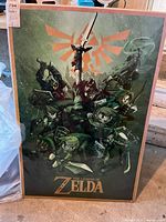 Full view of The Legend of Zelda framed poster displaying multiple characters and the series logo with a green background and orange crest.