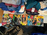 Eight Gold Key vintage comic books including multiple issues of "The Man from U.N.C.L.E." and one issue of "Star Trek" fanned out on a surface with other items in background.