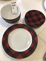 Stack of bowls, salad/dessert plates, and dinner plates showing red and black buffalo plaid pattern edges.