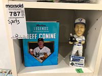 Photo showing Jeff Conine bobblehead and original box alongside Pat Borders bobblehead in uniform, both approximately 8 inches tall.