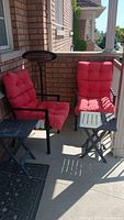 View of two outdoor metal frame chairs with red cushions on a patio, showing one heater nearby but not included.