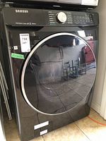 Full view of black stainless steel front-load washer showing chrome-trimmed door and control panel