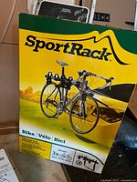 Front side of original box with branding and image of bike rack mounted on car trunk holding three bikes.