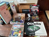Full overview of board games assortment showing Othello, multiple Ticket to Ride editions, Toilet Fishing Game, Table Top Curling, Yahtzee, Zombie Board game, Star Wars card game and Ick game