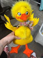 Full view of Annalee yellow plush duck figure held in hand showing body, feet, head, and wings