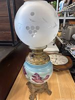 Full view of lamp showing frosted globe with grapevine design and hand painted milk glass floral base.