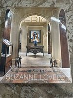 Front cover of the Artistic Interiors book showing an elegant interior design setting with two dog statues and framed artwork.