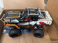 Photo shows the assembled LEGO Technic 4x4 Crawler model inside a box with visible decals and partly completed assembly.