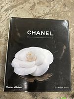 Front cover of Chanel book showing black background with white camellia flower and title text