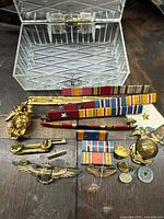 Clear photo showing assorted USMC military medals, campaign ribbons, and insignia including USMC eagles, globes, anchors, and a U.S. Navy aviator wing badge with metal and fabric materials.