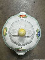 Top view of the tureen lid showing fruit decorations and yellow golf ball-shaped handle.