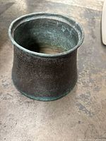 Full view of the vintage metal planter showing its tapered shape and greenish patina.