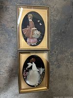 Full view of both vintage shell art pieces in gold tone oval frames showing a lady in bonnet and an angel figure gracefully posed.