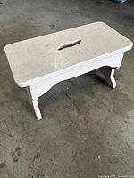 Side angle of vintage wooden footstool showing white painted finish and curved legs