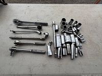 Full view of socket wrenches and sockets laid out on a plain surface