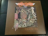 Front cover of the Aerosmith LP Toys in the Attic showing detailed illustrated attic scene with toys and stylized Aerosmith logo in orange.