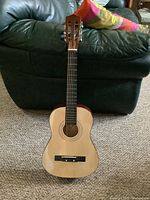 Full frontal image showing the entire acoustic guitar with gloss natural wood finish top and brown back and sides, standing upright.