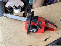 Red Homelite 330 chainsaw showing full side profile including chain bar, front and rear handles.