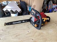 Full view of Homelite chainsaw showing 16 inch black bar with Homelite branding on a red body.