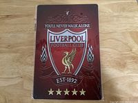 Front view of the rectangular Liverpool Football Club metal sign with club logo and slogan on red background.