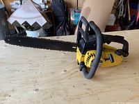 Full side view of the yellow and black Mastercraft chainsaw showing the entire chainsaw with 38cm bar on a wooden surface.