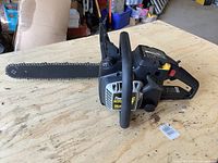 Side view of McCulloch Power Mac PM225-16 chainsaw placed on wooden surface showing full 16-inch bar and main housing.