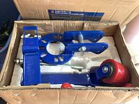 Top view of blue metal components with red roller wheel in original packaging.