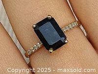 Ring on finger showing emerald-cut black diamond and accent diamonds