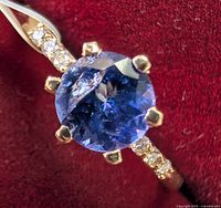 Close‐up of ring showing round mix cut tanzanite center and diamond accents