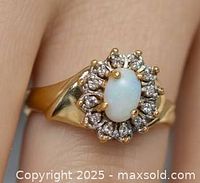 Front view of ring showing opal center and diamond halo on yellow gold band