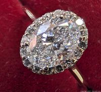 Close-up front view of oval center diamond and surrounding halo