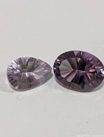 Top view of pear-shaped and oval-shaped amethyst gemstones showing color and faceting.