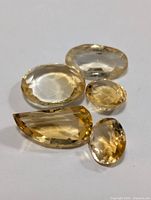 Five faceted citrine gemstones laid together showing different cuts and sizes
